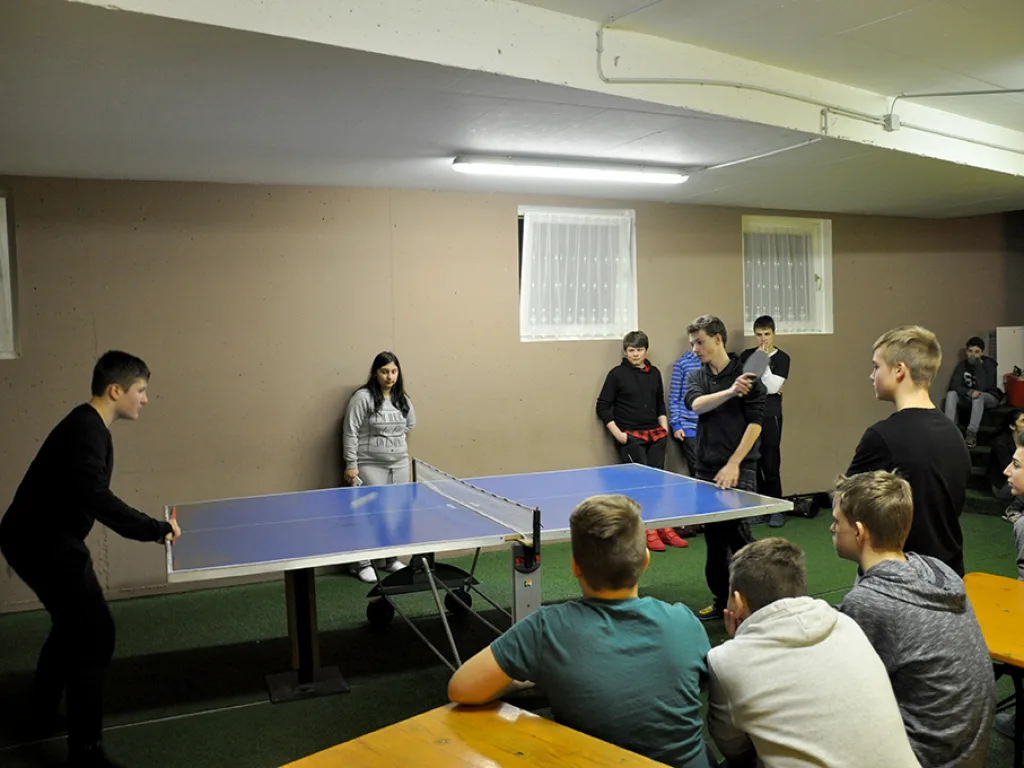 Tischtennisspiel im Aufenthaltsraum, weitere schauen zu.
